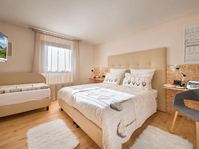 Modernes Schlafzimmer mit großem Bett, Fernseher an der Wand und eleganter Holzmöblierung.