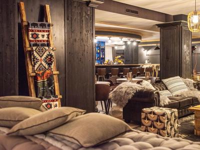 Gemütlicher Hotelbereich mit moosgrünen Sofas, Kissen und warmem Holzakzent unter sanfter Beleuchtung.