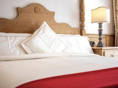 Ein gemütliches Hotelbett mit weißer Bettwäsche und einem roten Akzent vorne.