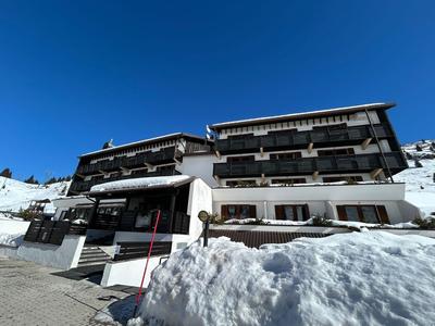 Hotelgebäude mit Balkonen, umgeben von Schnee unter klarem blauem Himmel.