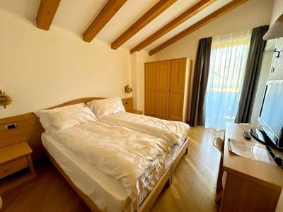 Gemütliches Hotelzimmer mit Doppelbett, Holzmöbeln und Balkon mit grünem Ausblick.