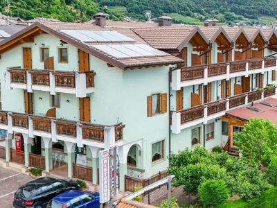 Mehrstöckiges Hotel mit Holzbalkonen in grüner, hügeliger Umgebung und Parkplätzen vorne.
