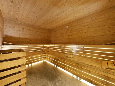 Helle Sauna mit hölzernen Sitzbänken und indirekter Beleuchtung innen.