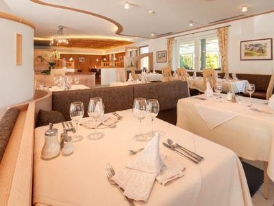 Helles Restaurant mit gedeckten Tischen, weißen Tischdecken und bequemen Sitzbänken.