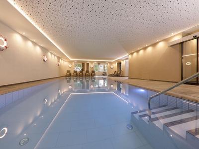 Innenpool in modernem Hotel mit beigen Wänden und Treppe ins Wasser.