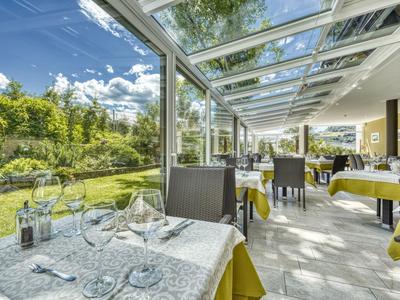 Nowoczesna część restauracyjna hotelu ze szklanym dachem i widokiem na zadbany ogród.