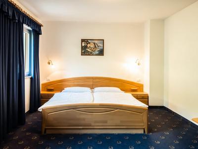 Helles Hotelzimmer mit einem Doppelbett, blauen Vorhängen und einem gerahmten Bild an der Wand.