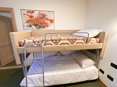 Hotelzimmer mit Etagenbett, Blumenbild an der Wand und grüner Teppichboden.