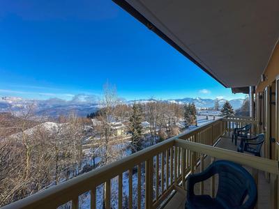 Balkon mit Stühlen bietet Blick auf verschneite Berge und blauen Himmel.