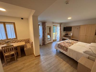 Gemütliches Hotelzimmer mit Doppelbett, Sitzecke und großem Schrank in warmen Farbtönen.