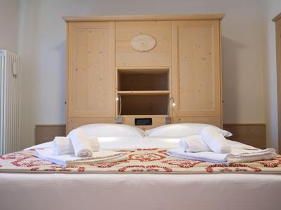 Gemütliches Hotelzimmer mit Doppelbett, Holzmöbeln und weißen Handtüchern.