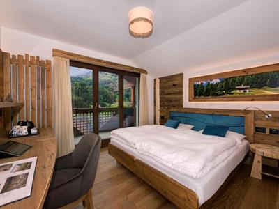 Habitación de hotel moderna con muebles de madera, cama cómoda y vista a la montaña.