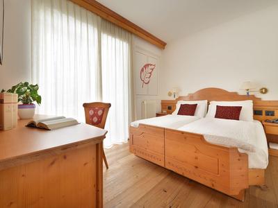 Habitación de hotel luminosa con muebles de madera y cama doble junto a una ventana grande.