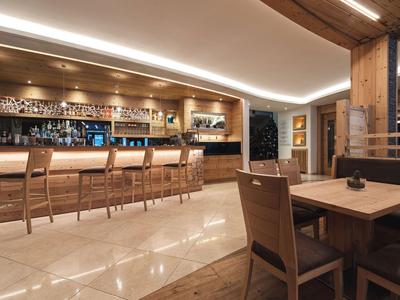 Área de bar moderna en un hotel con sillas de madera, mostrador y ambiente cálido.