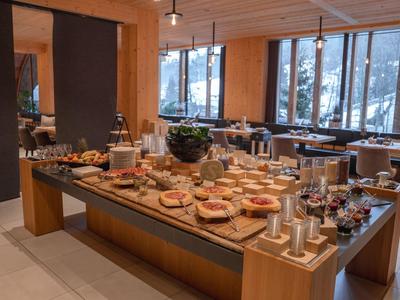 Buffet mit verschiedenen Frühstückszutaten in einem modernen Hotel mit Holzdekor und großen Fenstern.