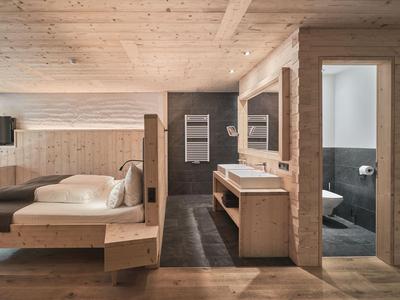 Modernes Hotelzimmer mit Holzmöbeln, Bett, Schreibtisch und Bad mit Dusche.