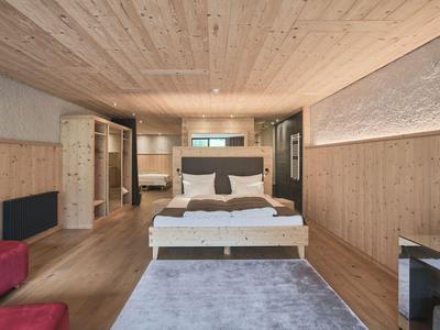 Hell eingerichtetes Hotelzimmer mit Holzverkleidung und großem Bett in der Mitte.