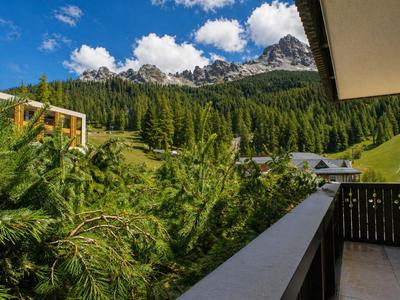 Balcone con vista su fitte foreste di pini e montagne sotto un cielo sereno.