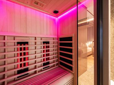 Sauna moderna con illuminazione LED rosa e panchine in legno nell'interno dell'hotel.