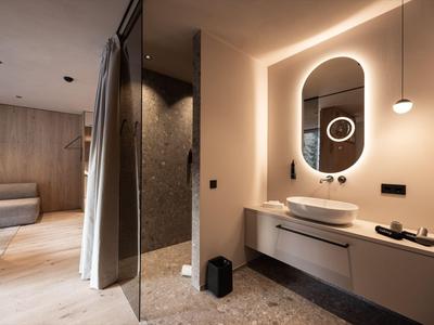 Area bagno moderna dell'hotel con specchio illuminato e doccia aperta.