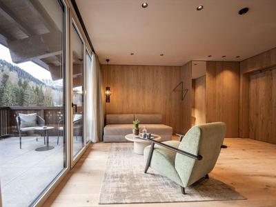 Camera d'hotel moderna con rivestimenti in legno e terrazza con vista sulle colline boschive.