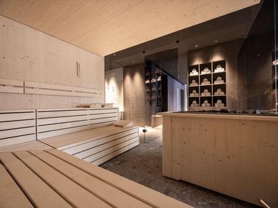 Sala sauna moderna con panche in legno chiaro, una doccia e illuminazione indiretta.