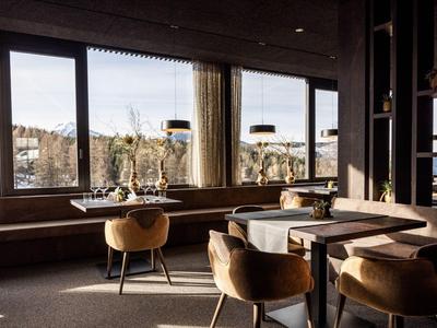 Sala hotel moderna con tavoli e sedie comode davanti a grandi finestre con vista.