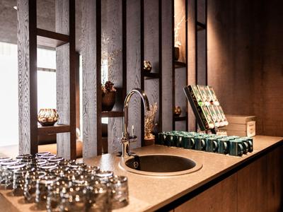 Bar elegante dell'hotel con bancone, bicchieri e rubinetto moderno sotto luce calda.