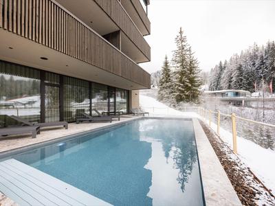Piscina moderna dell'hotel con vista su alberi coperti di neve e paesaggio innevato.
