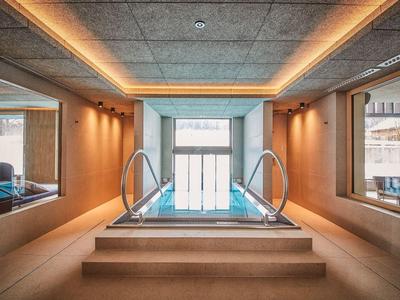 Moderní vnitřní bazén s schodištěm a nepřímým osvětlením v elegantním wellness prostředí.