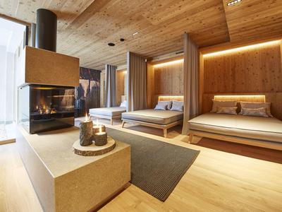 Moderní hotelový salonek s dřevěnými obklady, vestavěnými postelemi a krbem v teplém osvětlení.