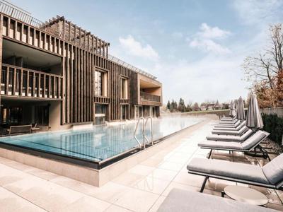 Moderní venkovní bazén s prosklenými hranami a lehátky v hotelu.