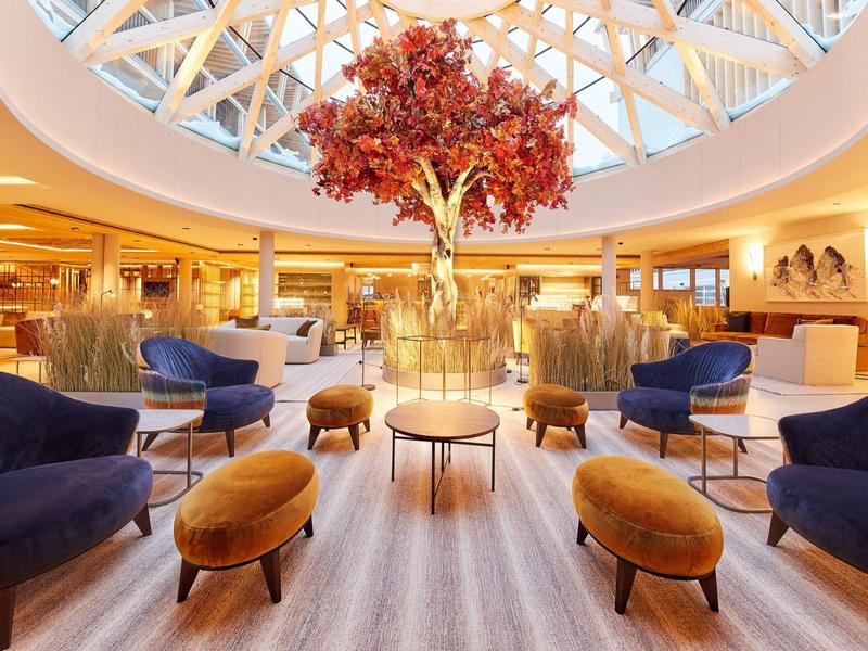 Prostorný hotelový salonek se skleněnou kopulí a modro-oranžovým posezením