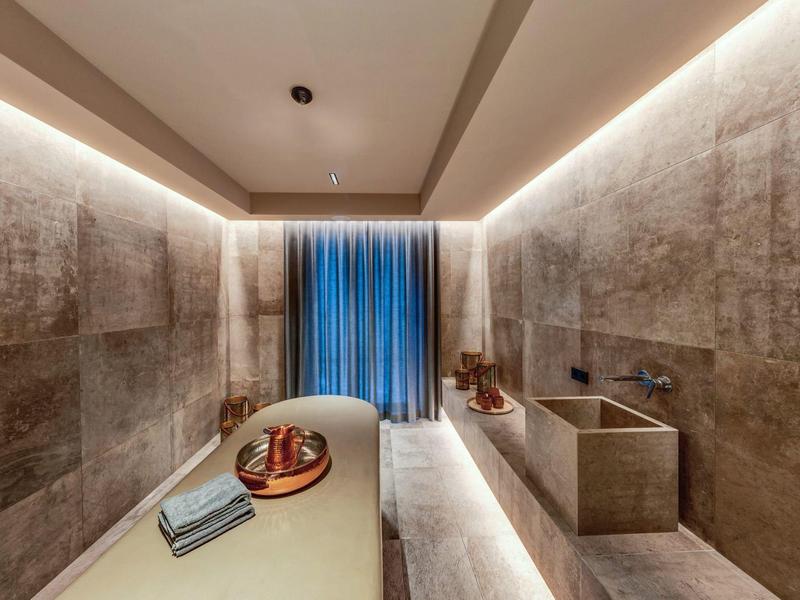 Moderní spa místnost s lehátkem, ručníky a jemným osvětlením.