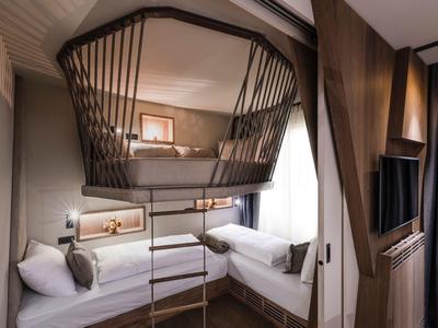 Modern hotel room with bunk beds, ladder, and cozy lighting.