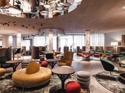 Modern hotel lobby with stylish seating, tables, and creative ceiling design.