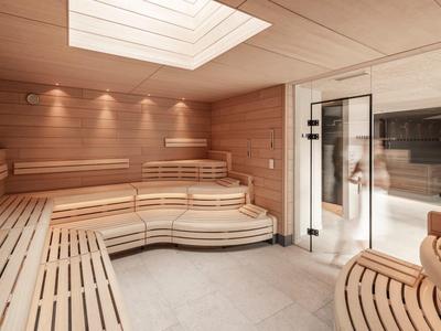 Modern sauna with light wood interior and glass door leading to a pool area.