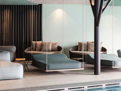 Modern indoor pool with hanging beds and a tree-shaped column feature.