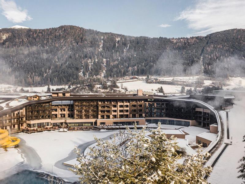 Large hotel in a snowy mountain landscape with forest and clear sky