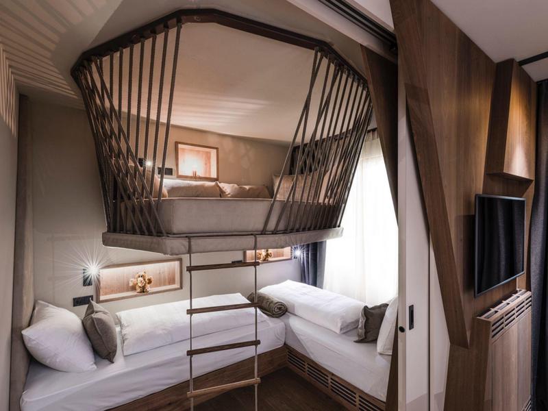 Modern hotel room with bunk beds, ladder, and cozy lighting.