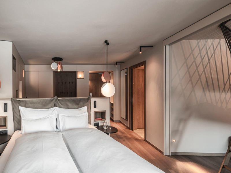 Modern hotel room with double bed, wooden floor, and interior staircase to the loft.