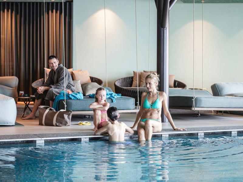 Family with children relaxing in an indoor hotel swimming pool.