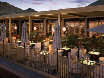 Terrasse eines modernen Restaurants mit Tischen, Stühlen und großen Sonnenschirmen bei Dämmerung.