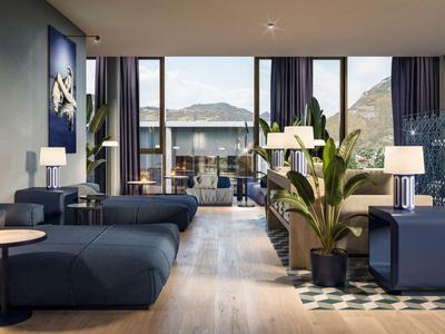 Modernes Wohnzimmer mit großen Fenstern, blauen Möbeln, Pflanzen und Holzboden.