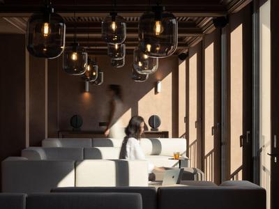 Interno moderno di un hotel con divani bianchi e lampade sospese in luce calda.