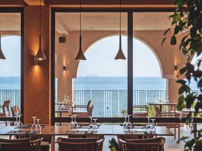 Sala da pranzo moderna con vista mare e lampade a sospensione eleganti.