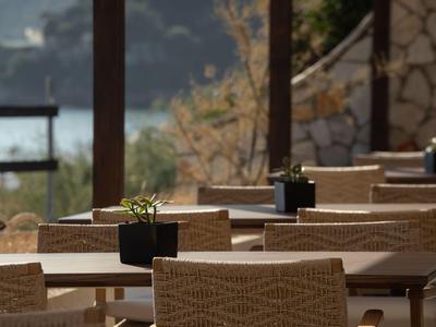 Terrasse avec des tables et des chaises tressées, décorée de petites plantes.