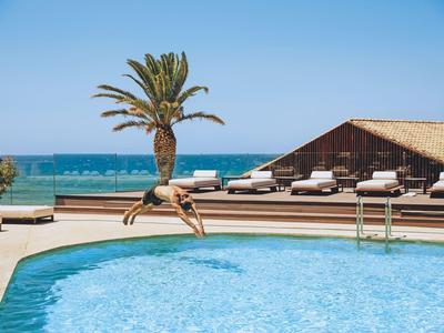 Personne sautant du bord de la piscine avec vue sur la mer et la terrasse ensoleillée