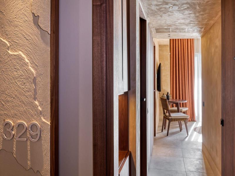 Pasillo con puertas de madera y silla, número de habitación 329 en una sección de pared texturizada.