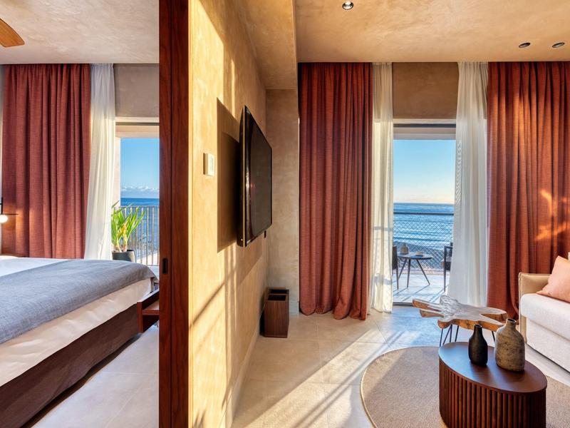 Habitación de hotel elegante con vista al balcón y al mar con luz solar.
